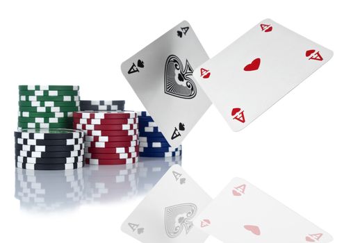 Two aces are about to land beside a stack of gambling chips. Isolated on white.