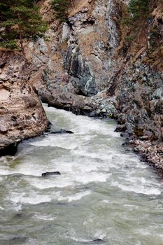 A curved river with stones which flows in a valley
