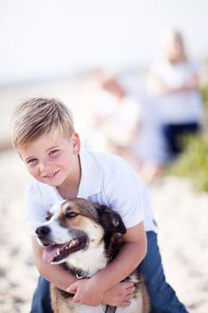 Handsome Young Boy Playing with His Dog at the Beach.
