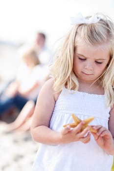 Adorable Little Blonde Girl with Starfish at The Beach.
