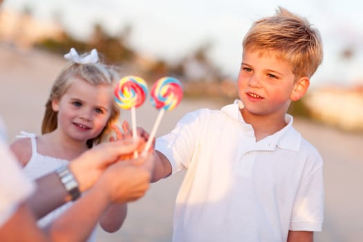 Cute Brother and Sister Picking out Lollipop from Their Mom at the Beach.