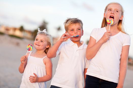 Cute Brother and Sisters Enjoying Their Lollipops at the Beach.