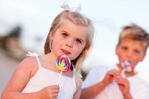 Cute Little Girl and Brother Enjoying Their Lollipops at the Beach.