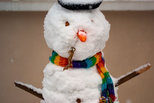 A snowman with a rainbow coloured scarf