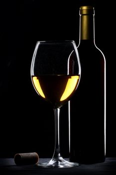 White wine bottle and glass silhouette over black background