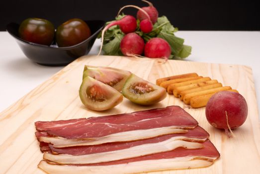 Smoked black forest ham on a chopping board surrounded by various ingredients