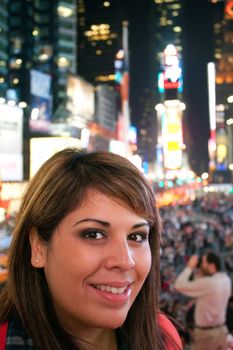 A young woman smiling as she stands in Times Square in New York City.  