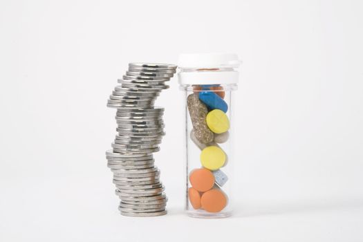 piled up money next to a bottle of colored pills
