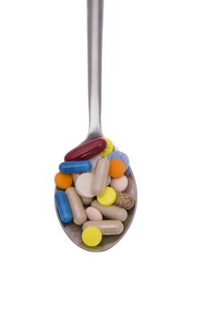 Teaspoon with pills and capsules isolated on white background
