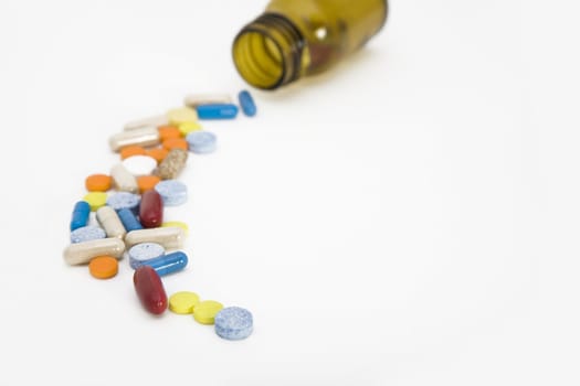a colorful stream of pills coming from a pill bottle - on a white background