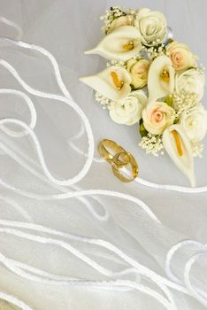 wedding rings and flowers decorations over bridal veil