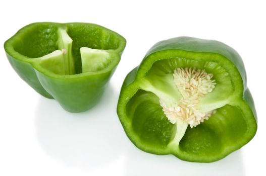 Close up capturing two halves of a green bell pepper arranged over white.
