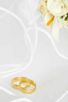 wedding rings and flowers decorations over bridal veil