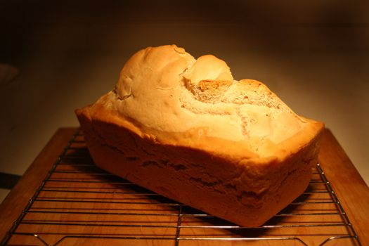 Fresh baked bread resting on a wire rack on a cutting board