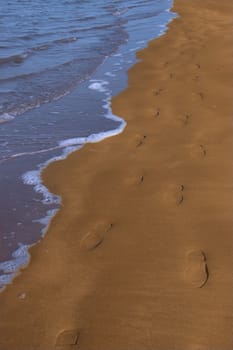 footprints left in the sand of an irish beach with the tide coming in