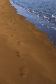 footprints left in the sand of an irish beach with the tide coming in