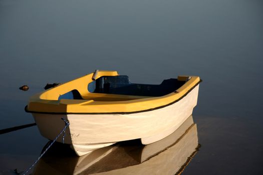 Small yellow and white boat on a tranquil river