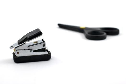 Stapler with safe scissors in the background isolated on white with shallow depth of field