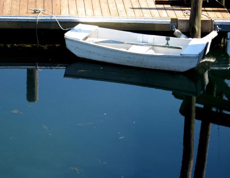 small skiff at dock on a calm morning, reflecting in water