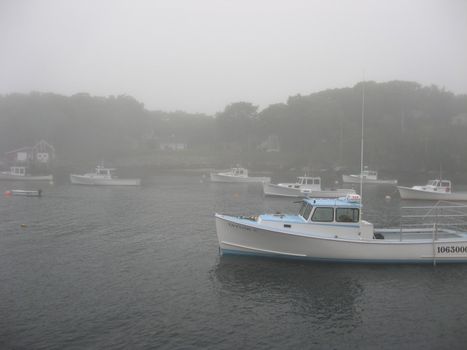 on a foggy morning, a lobster boat moored in the harbor