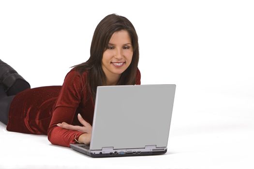 Beautiful young woman lying down and working on a laptop.