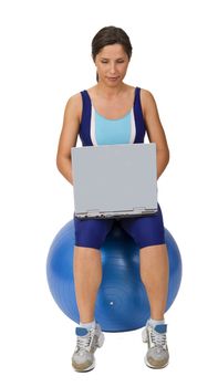 Active young woman using a laptop while sitting on a gym ball.Shot with Canon 70-200mm f/2.8L IS USM