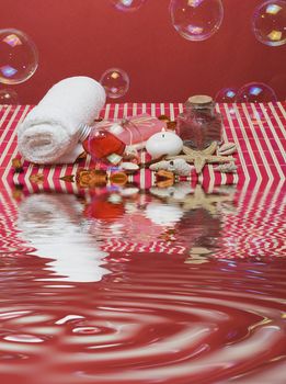 Still life about spa with some hygiene items in red and soap bubbles.