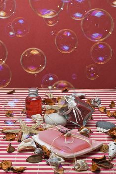 Still life about spa with some hygiene items in red and soap bubbles.