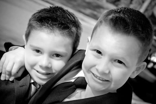 Two happy young boys dressed in suits with smiles on their faces.  Black and white.