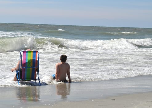 Mom and son sit on beach