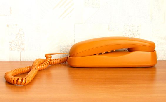 orange color stationary telephone on the table  