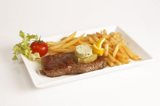 Grilled beef steak with french fries and sauce served in plate.