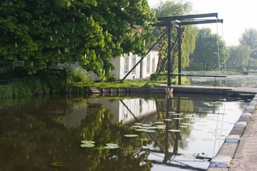 Dutch farm and lifting bridge with reflection on early morning in spring 