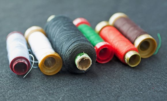 Closeup of rolls of sewing thread (focus on the black roll)