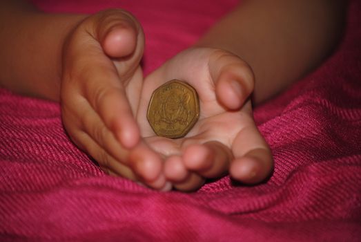 kids hand holding botwanian coin
