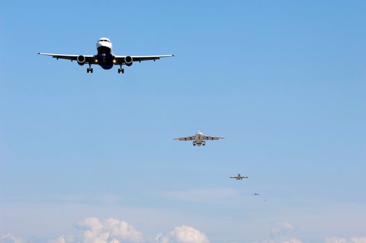 Many planes fly in a row ready to land.