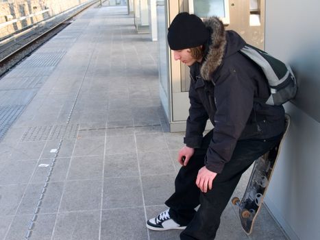 Deppressed young skater waiting at the trainstation