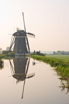 Dutch watermill at the waterside with reflection after sunrise 