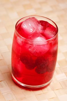 A glass of sparkling raspberry punch outdoors in a natural setting