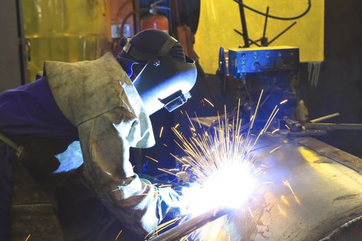 Labourer arc welding a tank