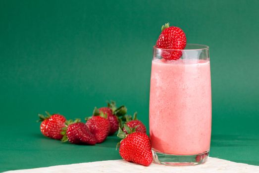 A strawberry smoothie isolated on a green background.