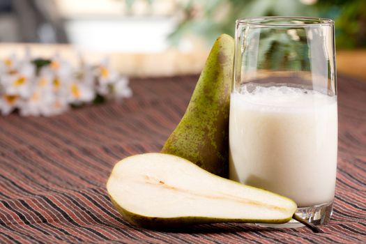 A tall glass of pear smoothie in a natural setting