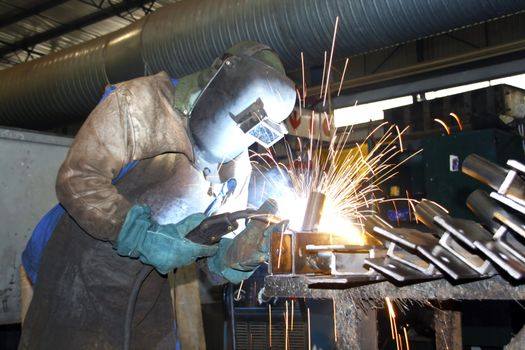 Man welding braces on a production line