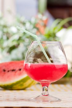 A glass of watermelon punch outdoors on a table