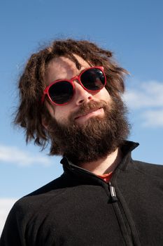 A funny portrait of a male with a full beard and sunglasses