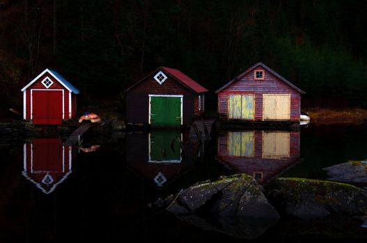 Three boathouses in the evening making reflections