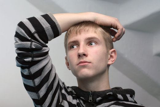 Portrait of young guy standing on gray background with staircase. No glamour, natural