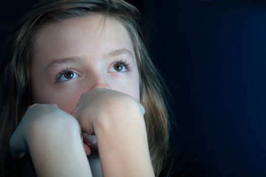 Nice young girl looking up portrait on dark background with copy space