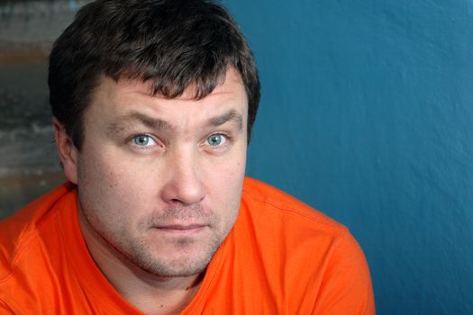 Serious young man portrait on background with old blue wall