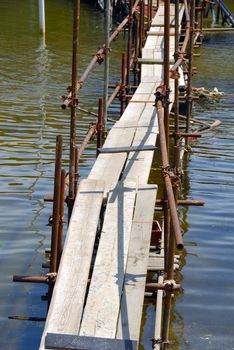 bridge across  water made from scaffolding and planks